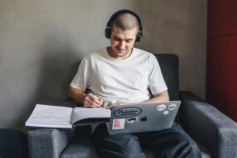 Studente sorridente che utilizza un computer portatile in una biblioteca luminosa.